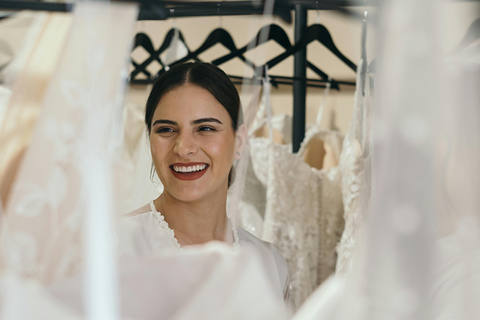 Bride smiling while trying on wedding dresses amid drama over wedding funding and family financial expectations.
