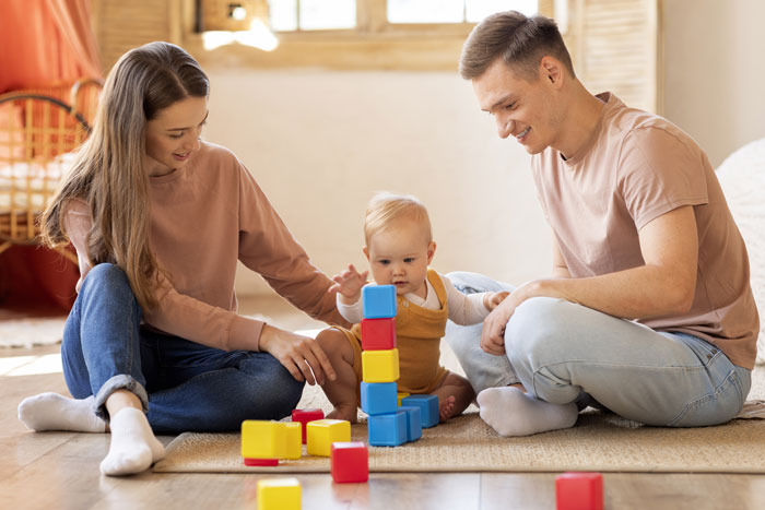 Couple babysitting nephew at home, playing with colorful blocks on the floor, enjoying family time together. Couple babysitting nephew at home, playing with colorful blocks on the floor, enjoying family time together.