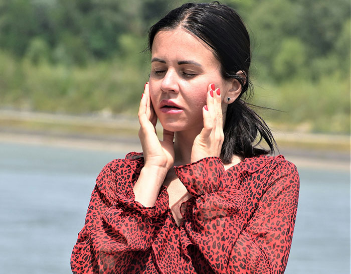 Woman in red blouse looking upset outdoors, reflecting on a ruined graduation day after hubby's unspoken seat change.
