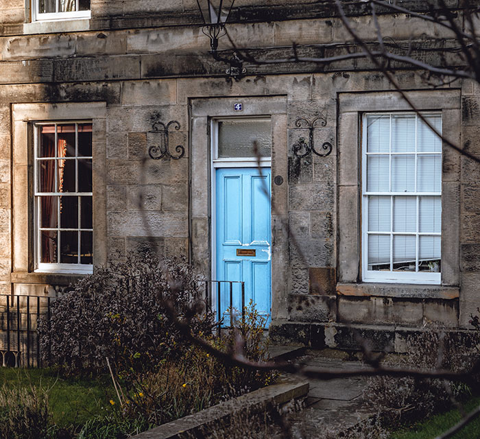 Stone house with blue front door and windows, surrounded by garden plants symbolizing kids' lies that got way too real.