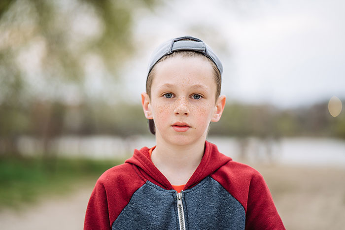 Young boy wearing a cap and hoodie outdoors, representing kids' lies that started off silly and got way too real.