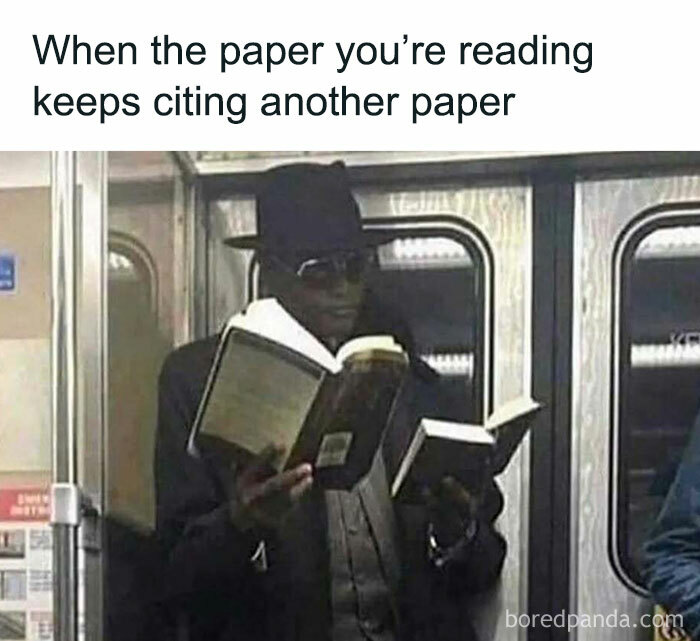 Man wearing sunglasses and a hat reading two books on a subway, illustrating intellectuals chuckling at memes.
