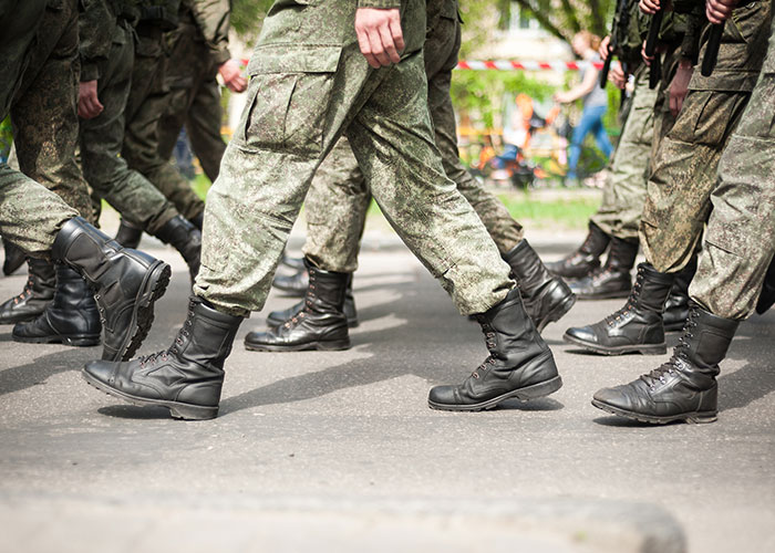 Soldiers marching in uniform boots on a paved street symbolizing moving away and rewriting life stories.