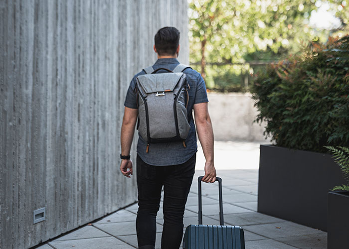 Man with backpack and suitcase walking away, symbolizing moving away and starting a new life chapter.