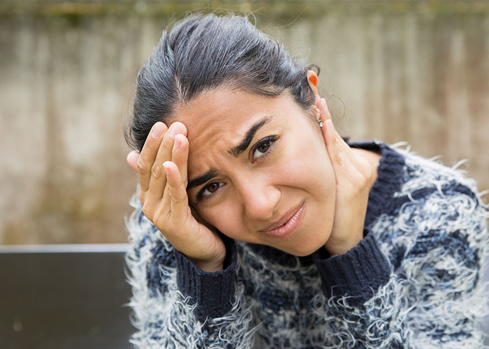 Woman looking worried and thoughtful, symbolizing people who moved away and changed their name to rewrite their life story.