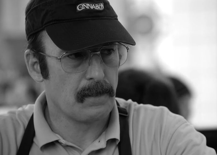 Man wearing glasses and a black cap with a mustache, representing people who moved away and changed their name.