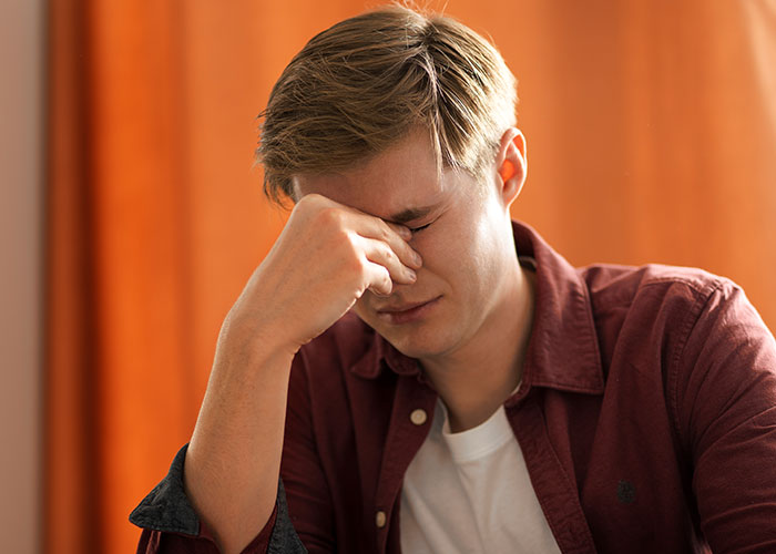 Young man with hand on face, appearing stressed or contemplative, illustrating moments people rewrote their life story.
