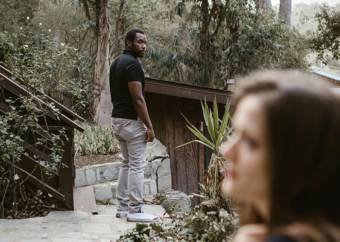 Man standing outdoors near wooden cabin, symbolizing moving away and changing identity in life story rewrite.