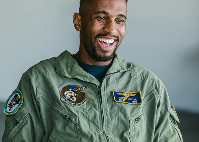 Man in military uniform smiling, representing people who moved away and changed their name to rewrite life story.