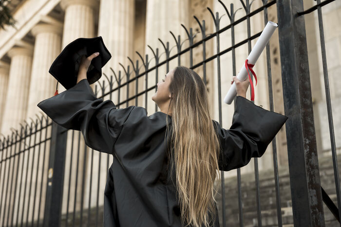 Woman in graduation gown holding diploma and cap, symbolizing wife who raised stepdaughters amid family conflict.