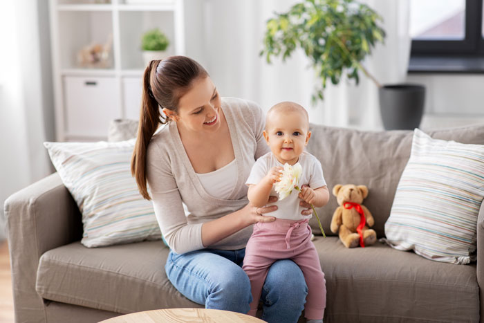 Woman babysitting a baby on a couch, illustrating child-free lady warning sis against too much babysitting.