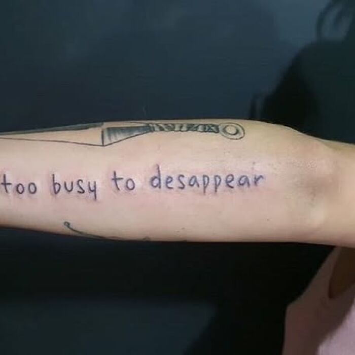 Tattoo of a knife and the phrase too busy to desappear on a person’s forearm, showing bizarre tattoo choices.