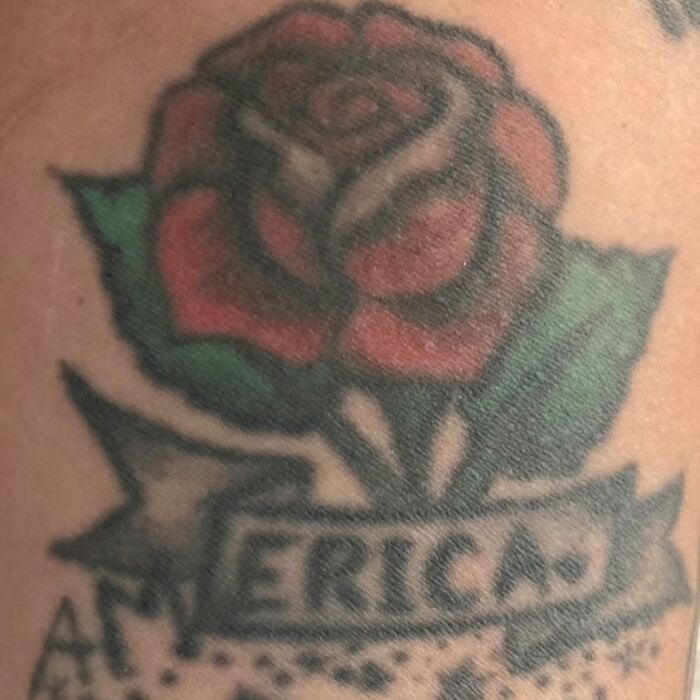 Close-up of a bizarre tattoo showing a red rose and a misspelled word on skin, highlighting unusual tattoo choices.