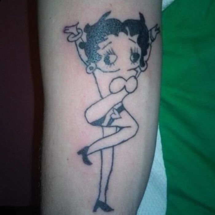 Tattoo of a distorted cartoon character on a forearm, showcasing one of the bizarre choices people made while getting tattoos.