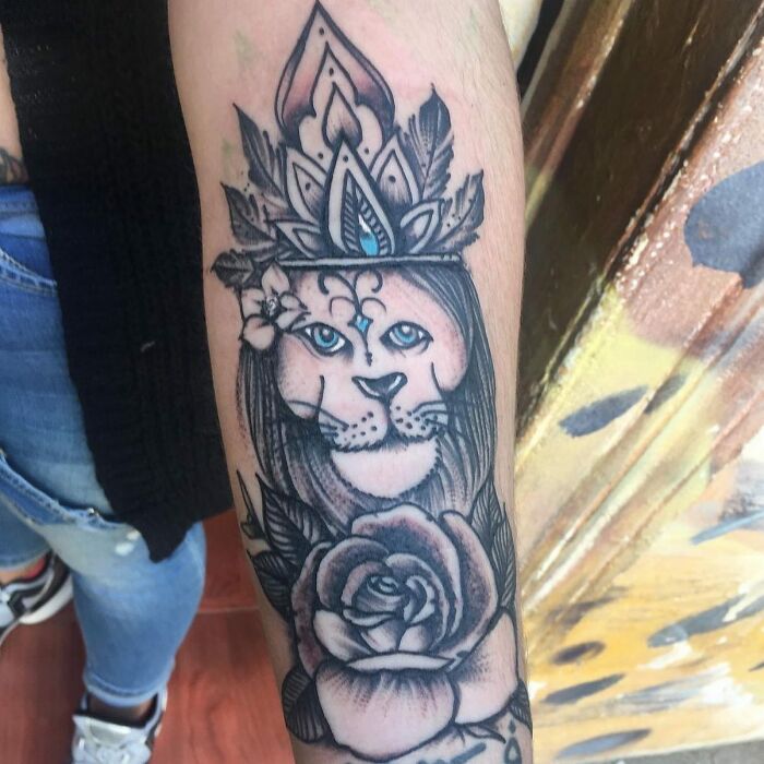 Intricate tattoo of a lioness with a crown and rose on forearm, showcasing bizarre tattoo choices and artistic design details.