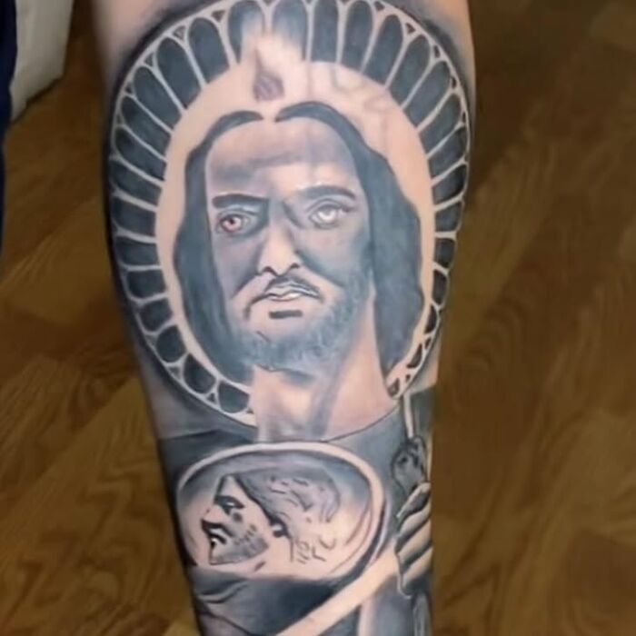 Tattoo of a distorted face with uneven eyes inside a halo design, showcasing bizarre choices people made while getting tattoos.