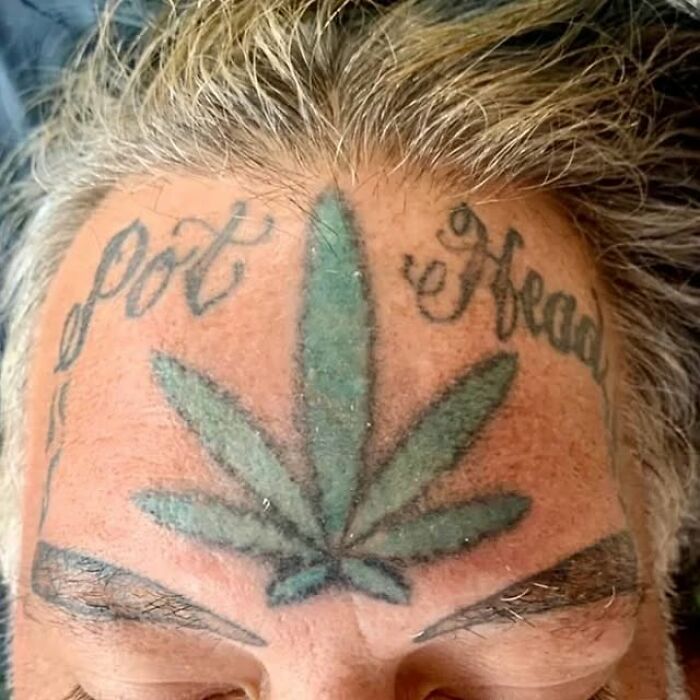 Green m*******a leaf tattoo on forehead with script text, showcasing one of the bizarre choices people made while getting tattoos.