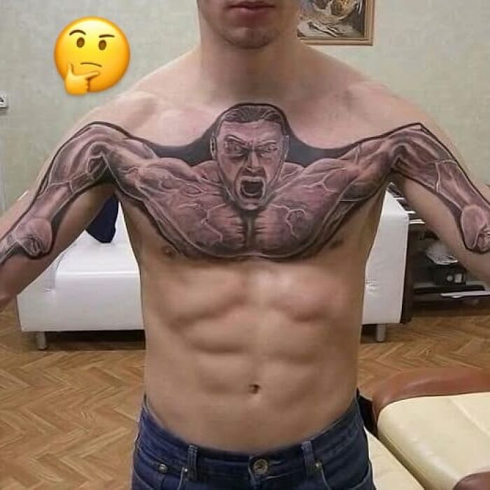 Man with bizarre tattoo of a muscular figure spanning chest and arms, showcasing unusual tattoo choices on his upper body.