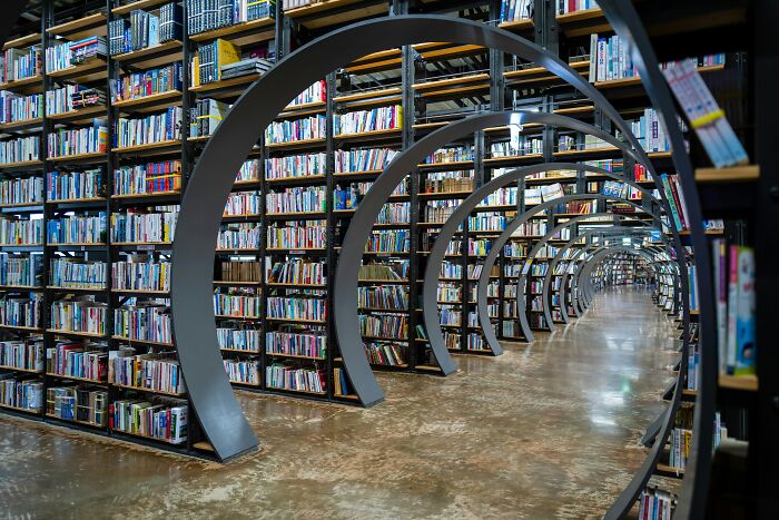 Grandiose library interior with circular metal arches and rows of bookshelves filled with colorful books.