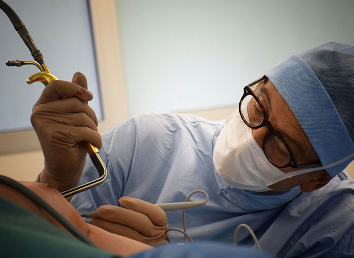 Surgeon wearing glasses and mask performing a detailed procedure highlighting weird facts about the human body.