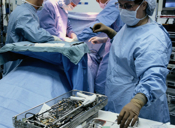 Surgeons in sterile gowns performing surgery with medical tools, illustrating weirdest facts about the human body.