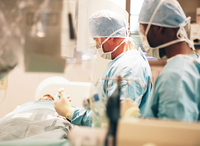 Two surgeons in scrubs and masks performing surgery, highlighting weird facts about the human body.