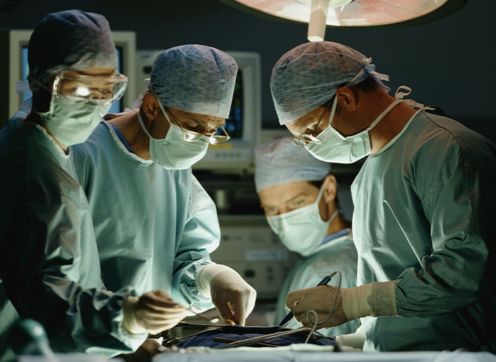Team of surgeons wearing scrubs and masks performing surgery, highlighting weirdest facts about the human body.