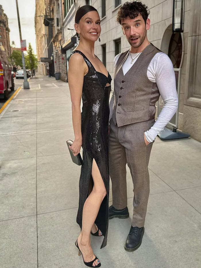 Hugh Jackman&rsquo;s new girlfriend in a black dress and heels posing with a man on a city sidewalk.