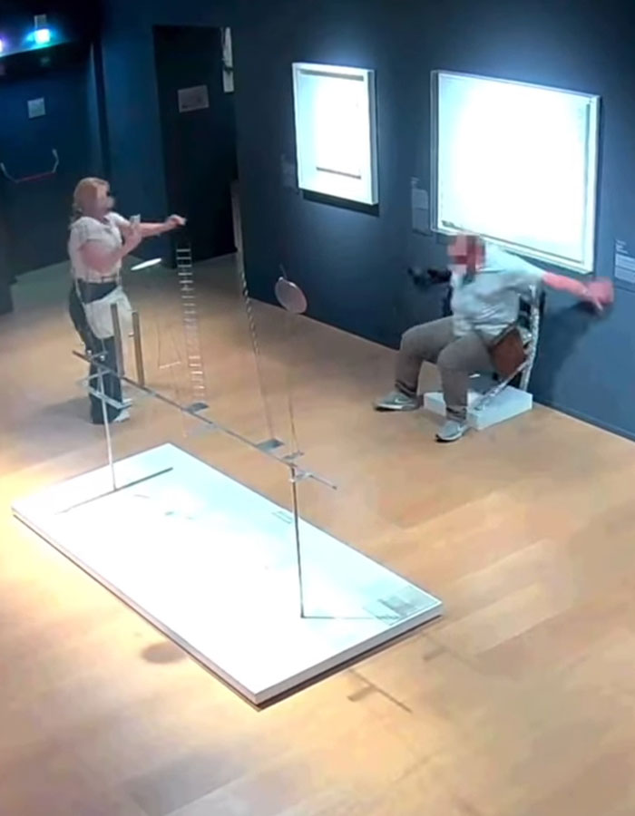 Tourist sitting on crystal-covered Van Gogh chair in Italian gallery with person reacting nearby.