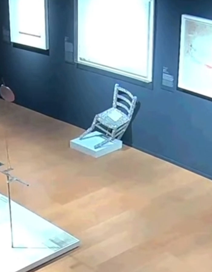 Crystal-covered Van Gogh chair broken in Italian gallery with art pieces displayed on navy blue walls.