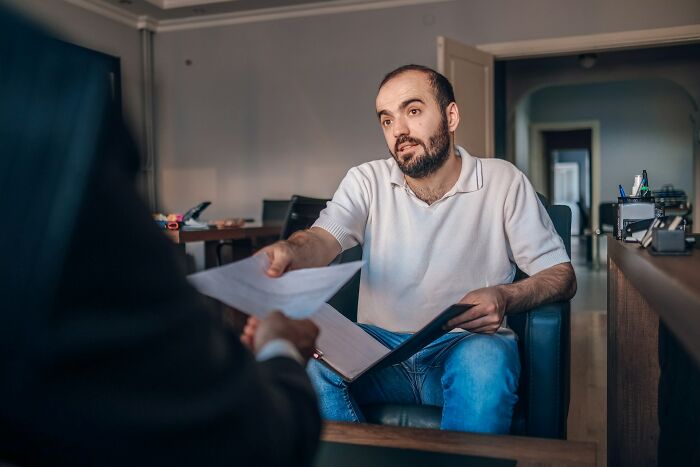 Man handing over a document while discussing sneaky things found by people who read terms and conditions carefully.