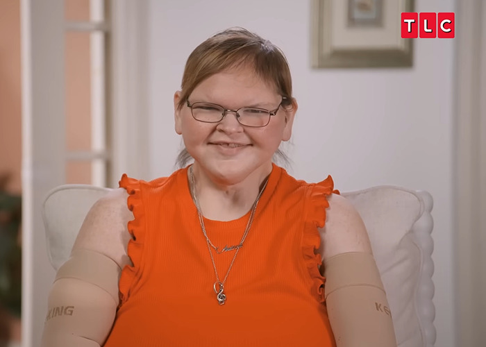 Star from 1000-lb Sisters smiling warmly, wearing glasses and an orange top in a TLC interview setting. Star from 1000-lb Sisters smiling warmly, wearing glasses and an orange top in a TLC interview setting.
