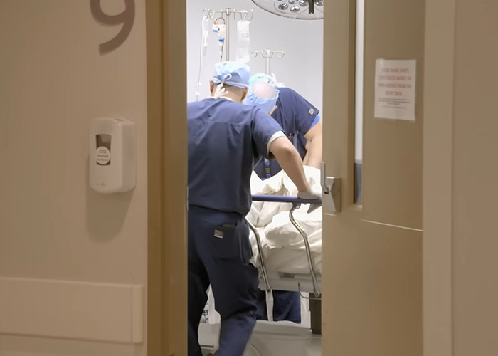 Medical staff in scrubs pushing a patient on a hospital bed during the 8-hour surgery of 1000-lb Sisters star transformation. Medical staff in scrubs pushing a patient on a hospital bed during the 8-hour surgery of 1000-lb Sisters star transformation.