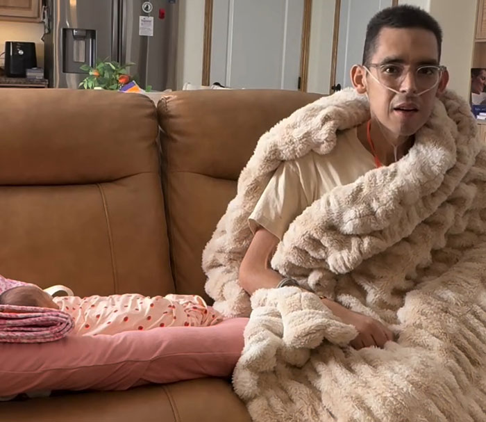 Tanner Martin wrapped in blanket sitting on couch beside newborn baby in hospital setting after birth announcement. Tanner Martin wrapped in blanket sitting on couch beside newborn baby in hospital setting after birth announcement.
