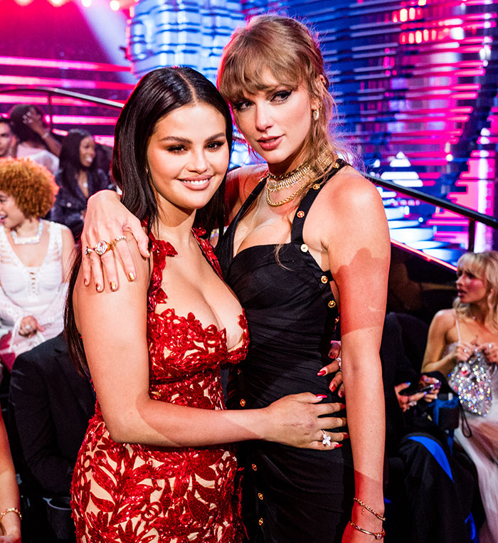 Taylor Swift and Selena Gomez posing together at a colorful event highlighting wealth display during the Eras Tour. Taylor Swift and Selena Gomez posing together at a colorful event highlighting wealth display during the Eras Tour.