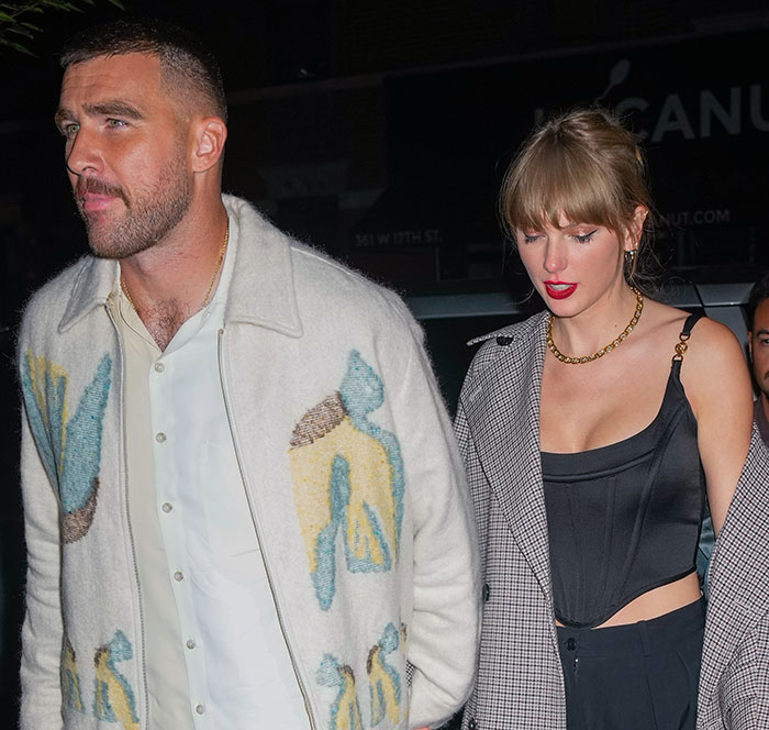 Taylor Swift and Travis Kelce walking together at night, sparking rumors of a secret marriage after invitation leak.