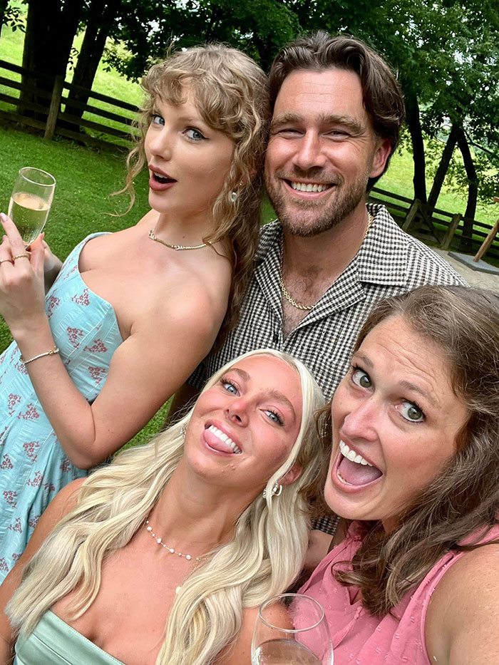 Taylor Swift and Travis Kelce with friends outdoors, smiling and holding drinks amid rumors of secret marriage.
