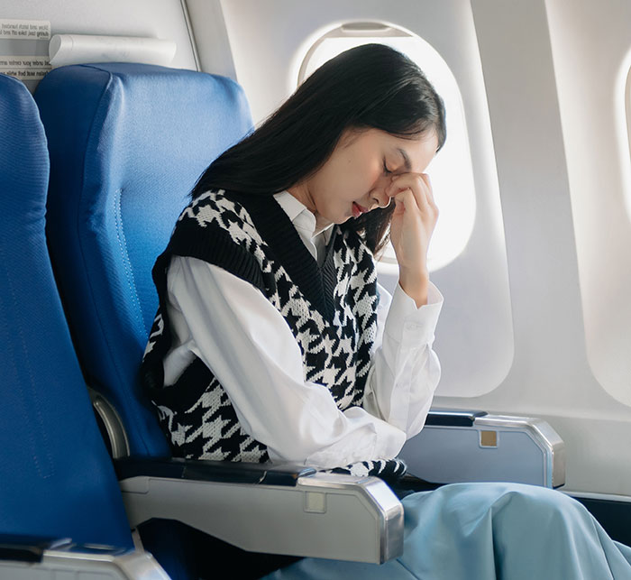 Young woman looks stressed sitting in economy class on a family vacation after sibling upgraded to business class. Young woman looks stressed sitting in economy class on a family vacation after sibling upgraded to business class.