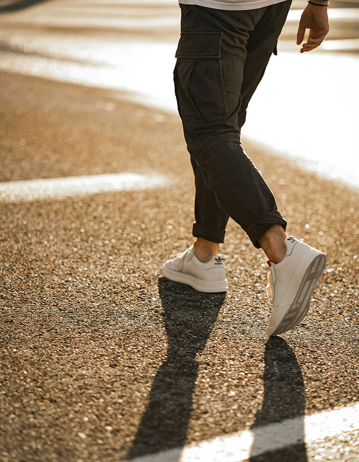 Person walking on sunlit pavement wearing white sneakers, illustrating Japanese walking trend benefits over 10000 steps a day. Person walking on sunlit pavement wearing white sneakers, illustrating Japanese walking trend benefits over 10000 steps a day.