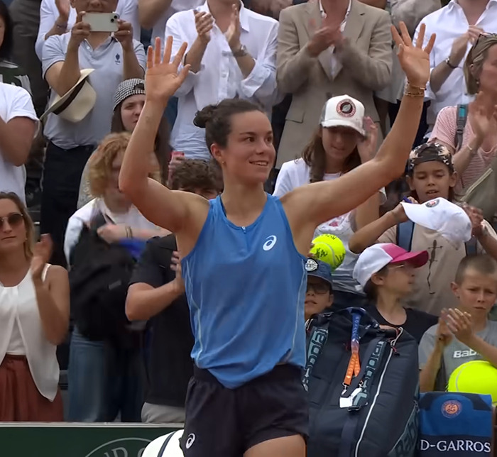 Tennis star raising hands and smiling to crowd after match amid opponent commenting on her odor mid-match.