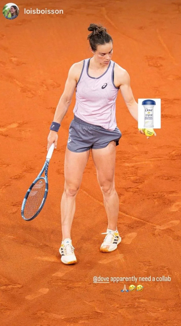 Tennis player on clay court holding racquet and deodorant, referencing opponent comment on her odor during match.