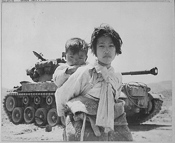 Two children in front of a tank during wartime, a haunting and creepy photo from the past with unsettling emotions.