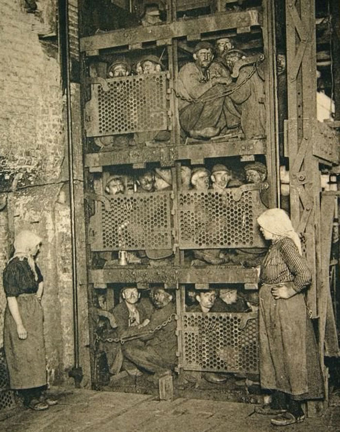 Vintage black and white photo showing miners crowded in a cage elevator, an incredibly creepy and unsettling scene from the past.