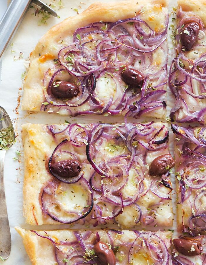 Close-up of pizza slices topped with olives and red onions, part of disgusting food pics that might ruin appetite.