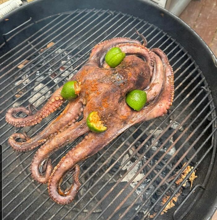 Grilled octopus with lime pieces on a barbecue grill, showing unusual and disgusting food pics.