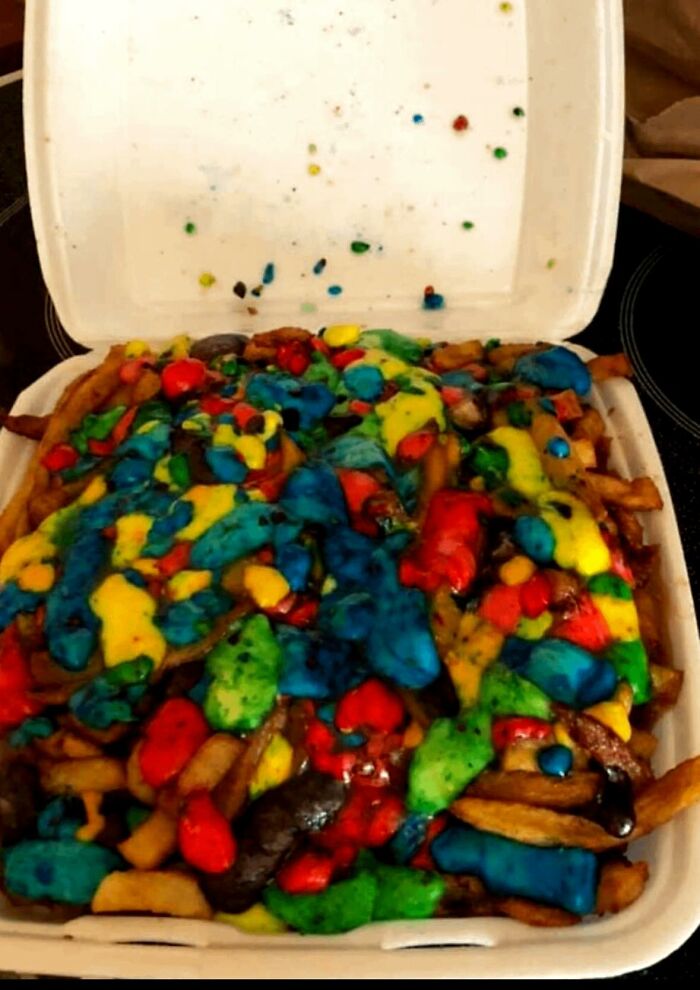 Takeout container filled with fries covered in brightly colored sauces in a disgusting food pics collection.