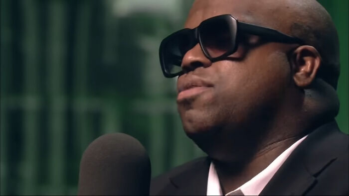 Man wearing large sunglasses speaking into microphone in studio setting, reflecting things learned embarrassingly late.