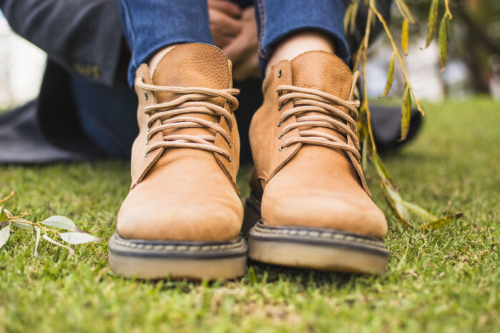 Close-up of tan boots on grass with blurred casual outfit in the background, illustrating things learned embarrassingly late.