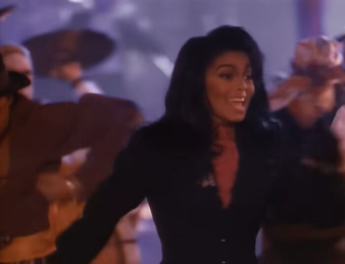 A joyful woman dancing with others in a lively scene, capturing moments of things learned embarrassingly late.