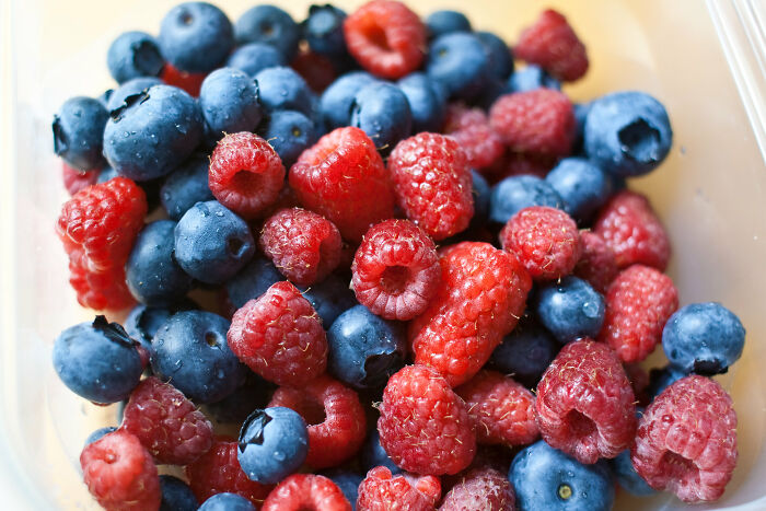 Close-up of fresh blueberries and raspberries mixed in a container, illustrating things learned embarrassingly late about fruit.